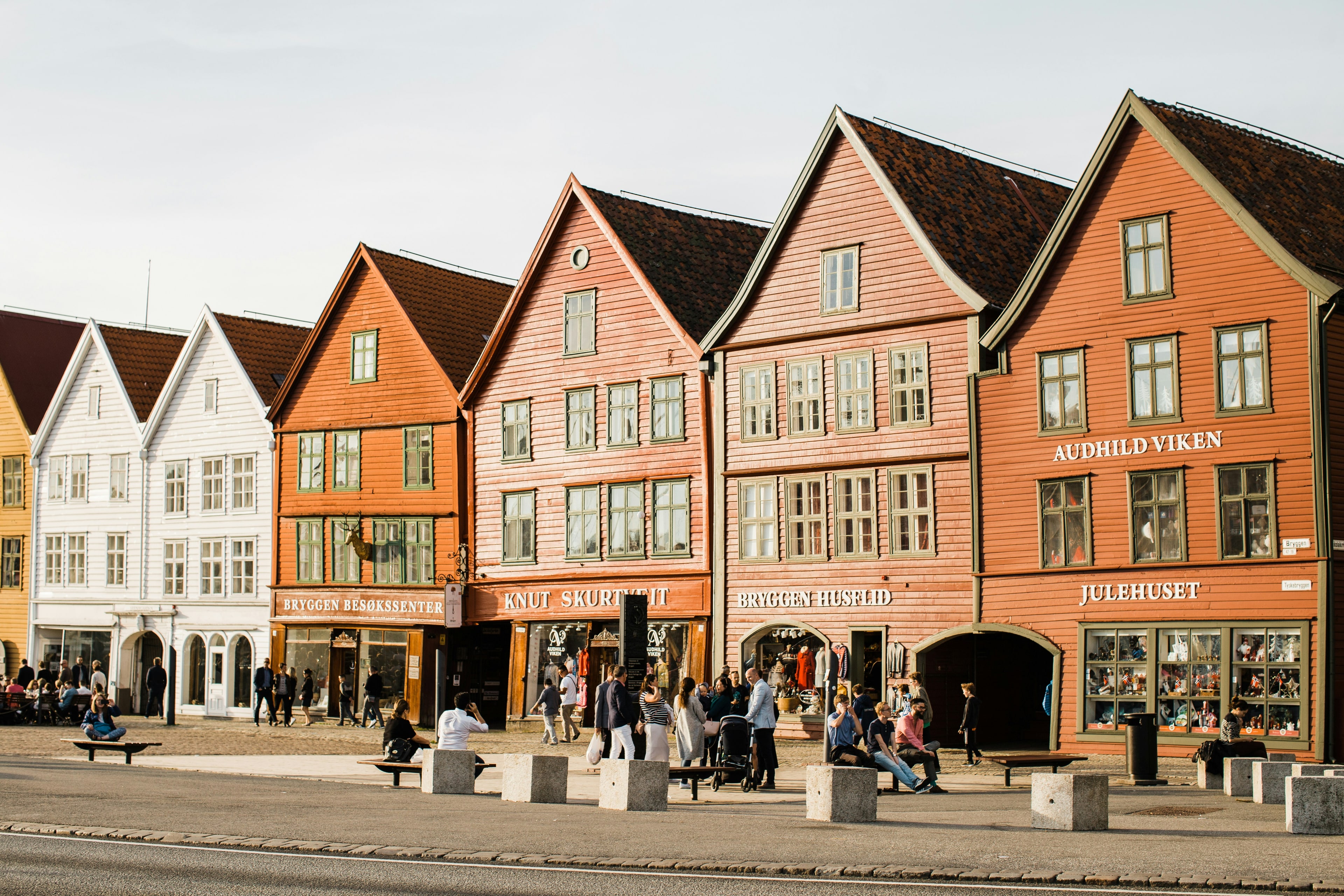 Fargerike historiske trehus i rekke ved Bryggen i Bergen med butikkskilt og spisse tak